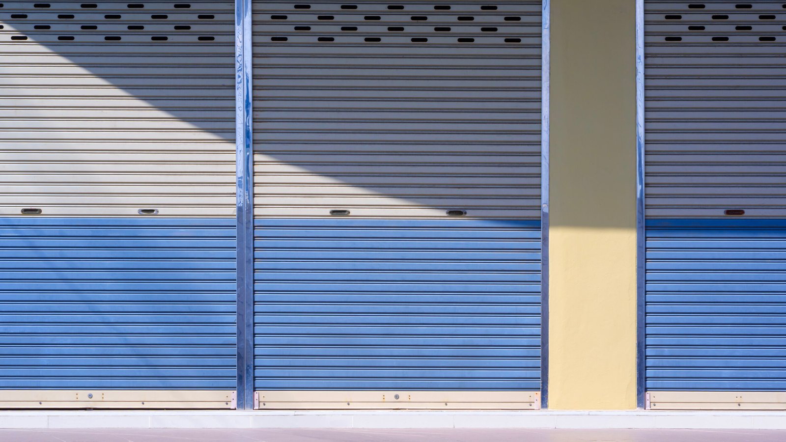Roller shutter doors of commercial building background with light and shadow on surface, front view with copy space